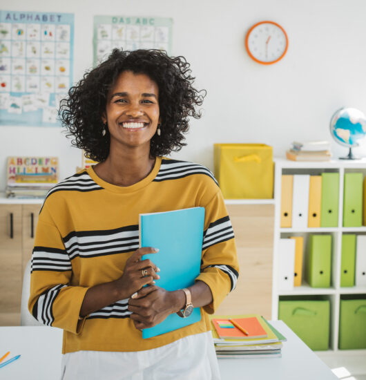 Teacher at classroom sitting on desk, preparing for next school year.