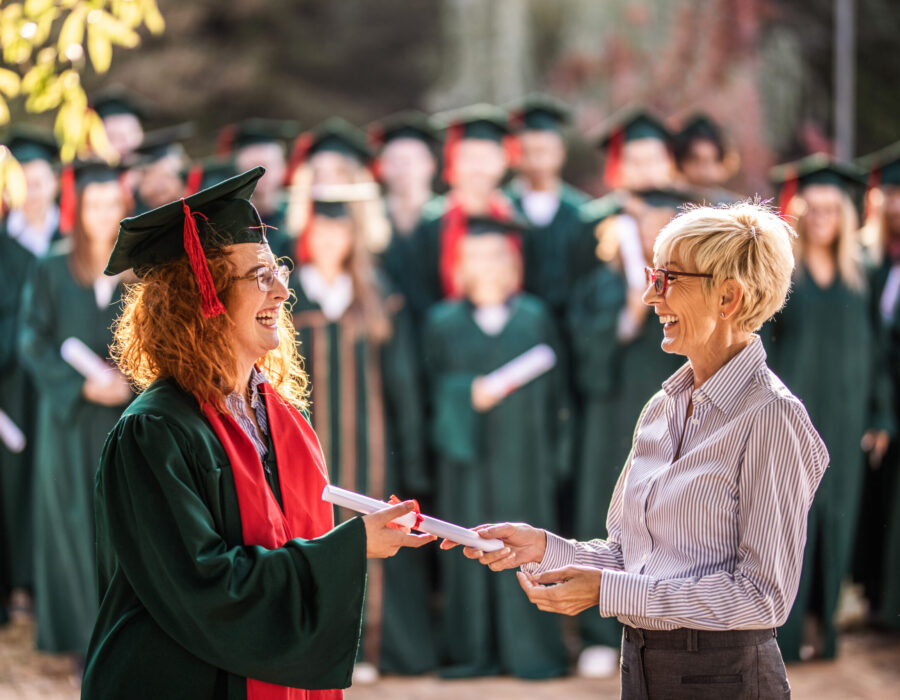 Smiling professor giving diploma to student