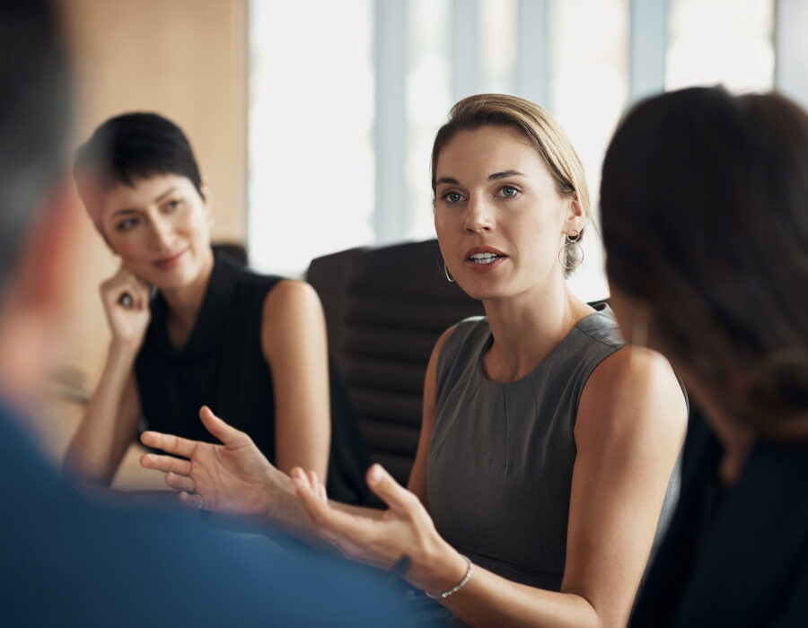 Woman offering advice around a conference table at work while others listen attentively