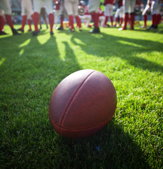 Photo of football in foreground with team in background