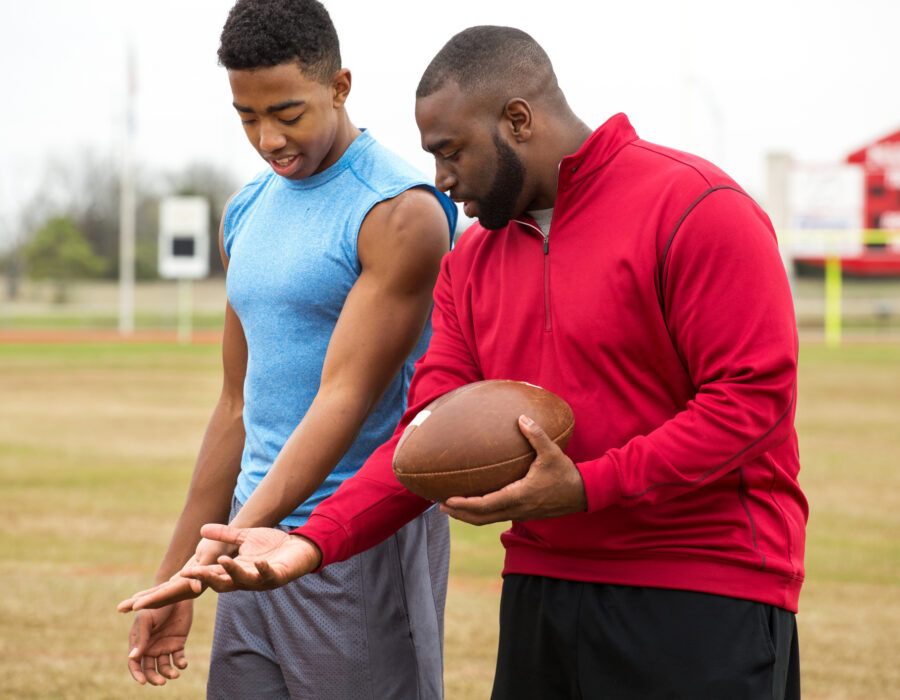 Coach giving tips to an athlete on football techniques